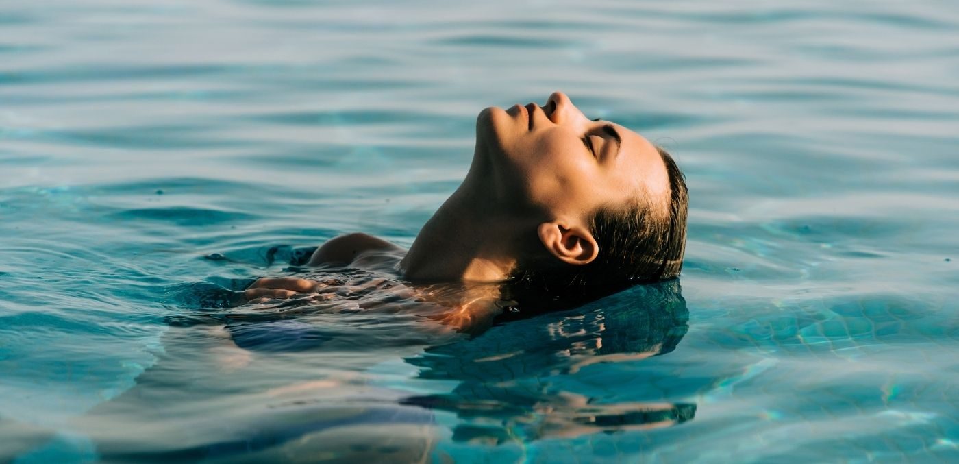 woman submerging head in a pool
