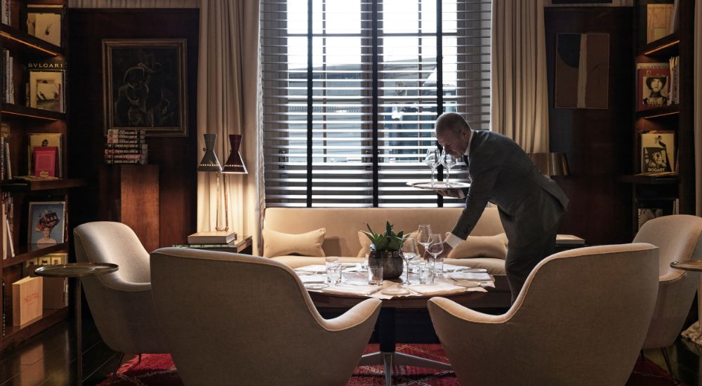 Butler laying glasses in the dining area at JK Place Rome