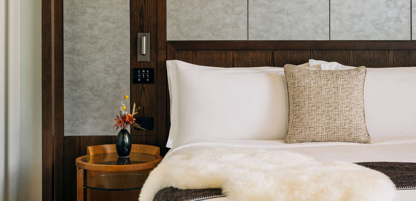 white pillow and a fur blanket on a bed.