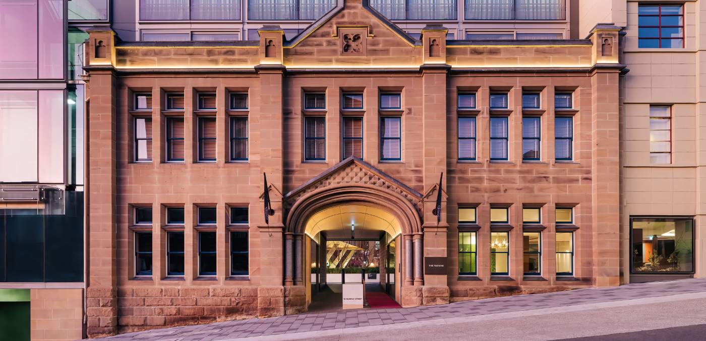 a sandstone building with red carpet rolling through the entryway